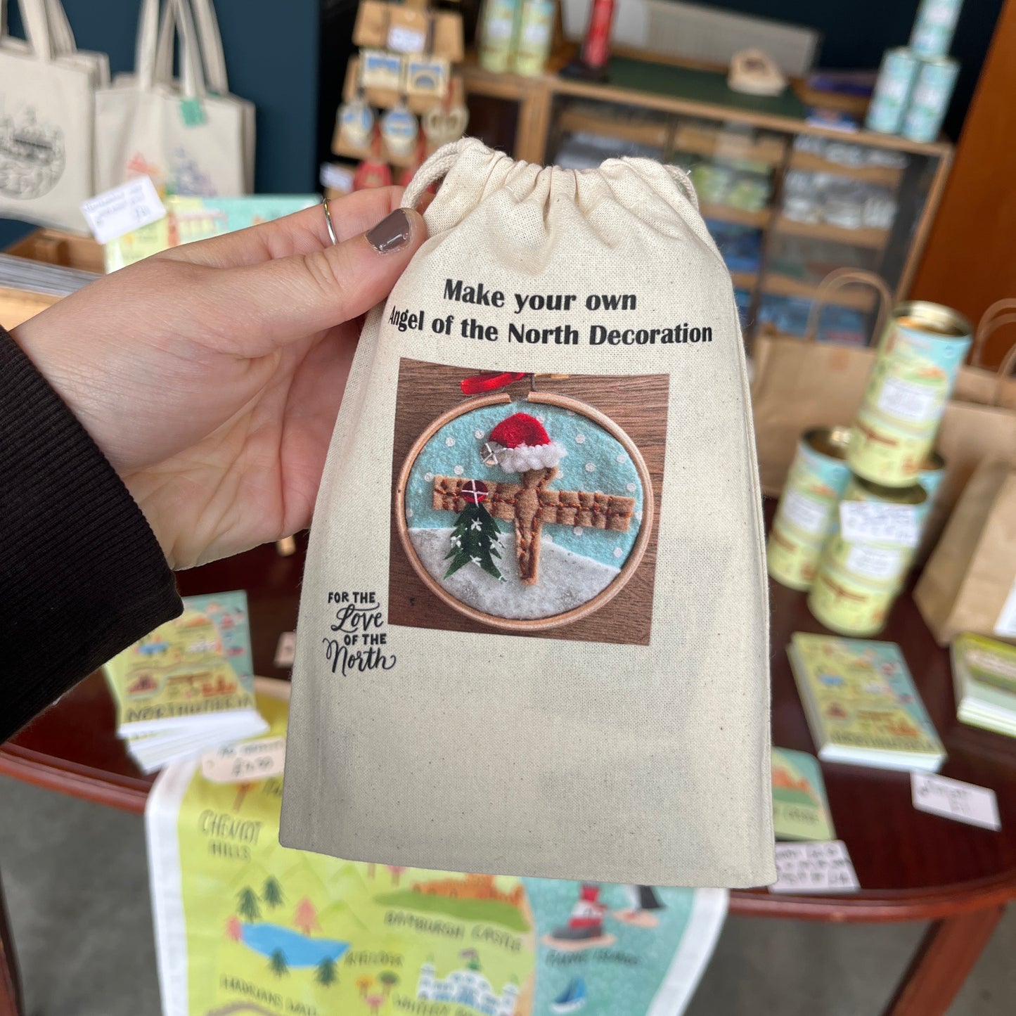 Hand holding a decorative bag with a design and text in a store setting