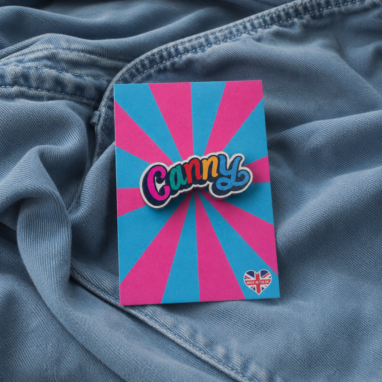Colorful 'Canny' pin badge on blue fabric