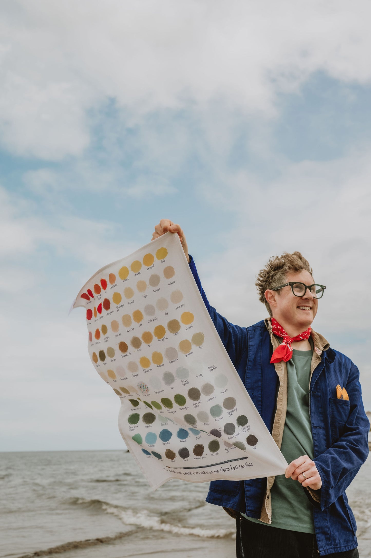 Person holding a color swatch tea towel by the sea