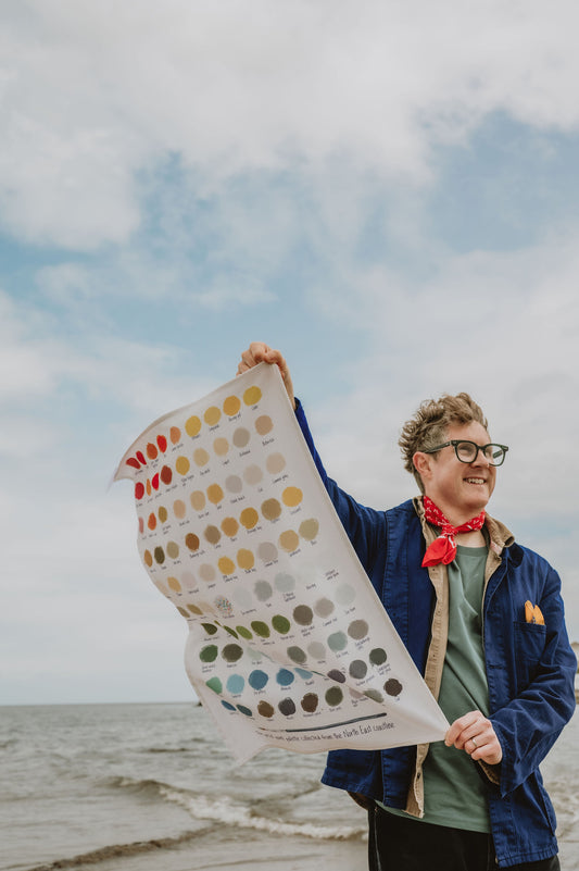 Person holding a color swatch tea towel by the sea
