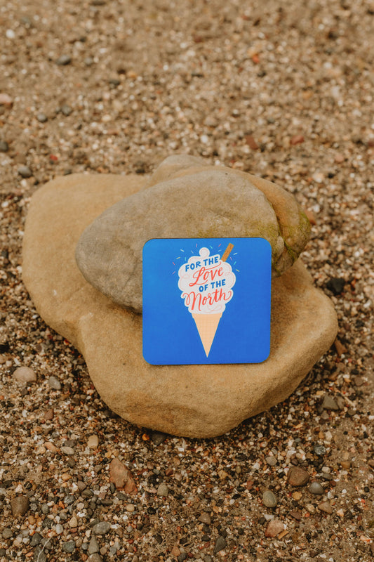 Coaster with a blue background and illustrated ice cream cone reading “For the Love of the North.”