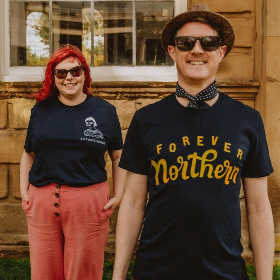 Two adults, one male and one female, standing close to each other. The male is wearing sunglasses and a navy T-shirt with 'FOREVER Northern' printed in yellow.