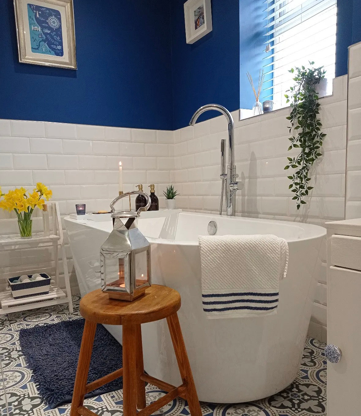 Bathroom with a freestanding bathtub, wooden stool, and decorative elements.