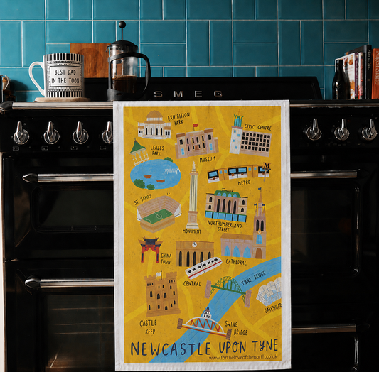 Tea towel with Newcastle upon Tyne illustrations hanging on a black Smeg oven.