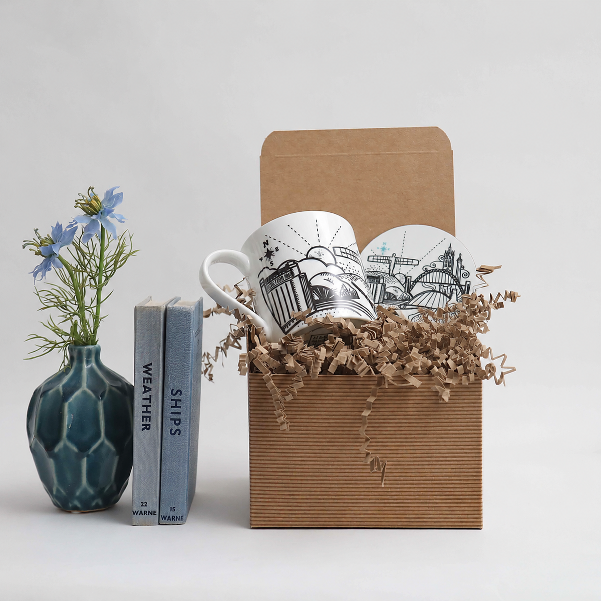 Gift set with mugs, books, and a vase on a light gray background