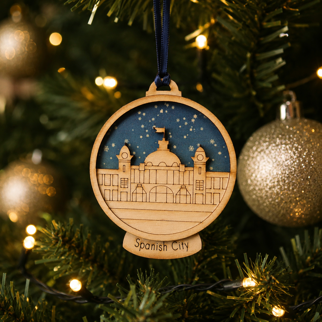 Wooden ornament of Spanish City on a Christmas tree with lights.