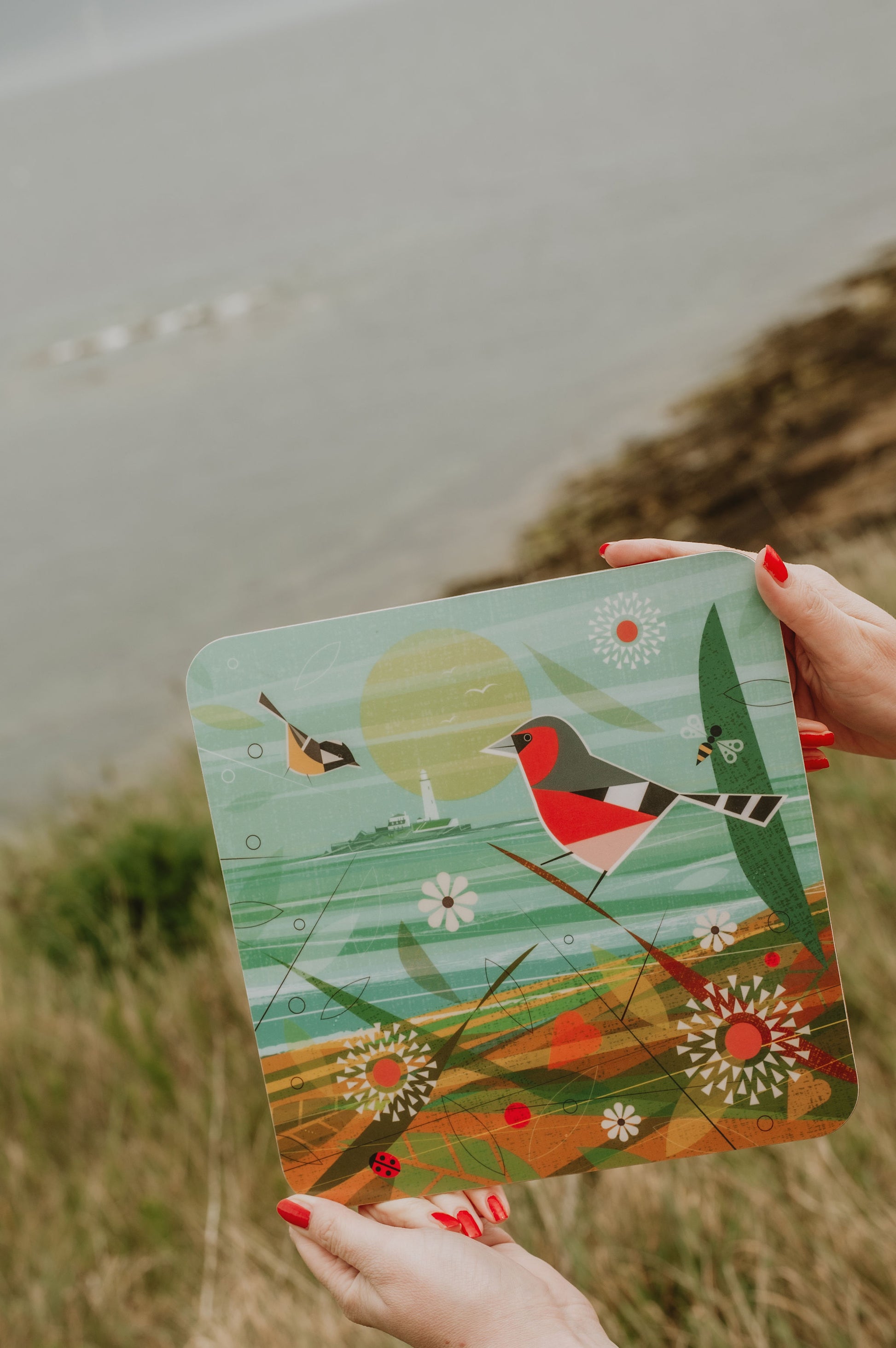 Person holding a colorful placemat with nature-themed design outdoors