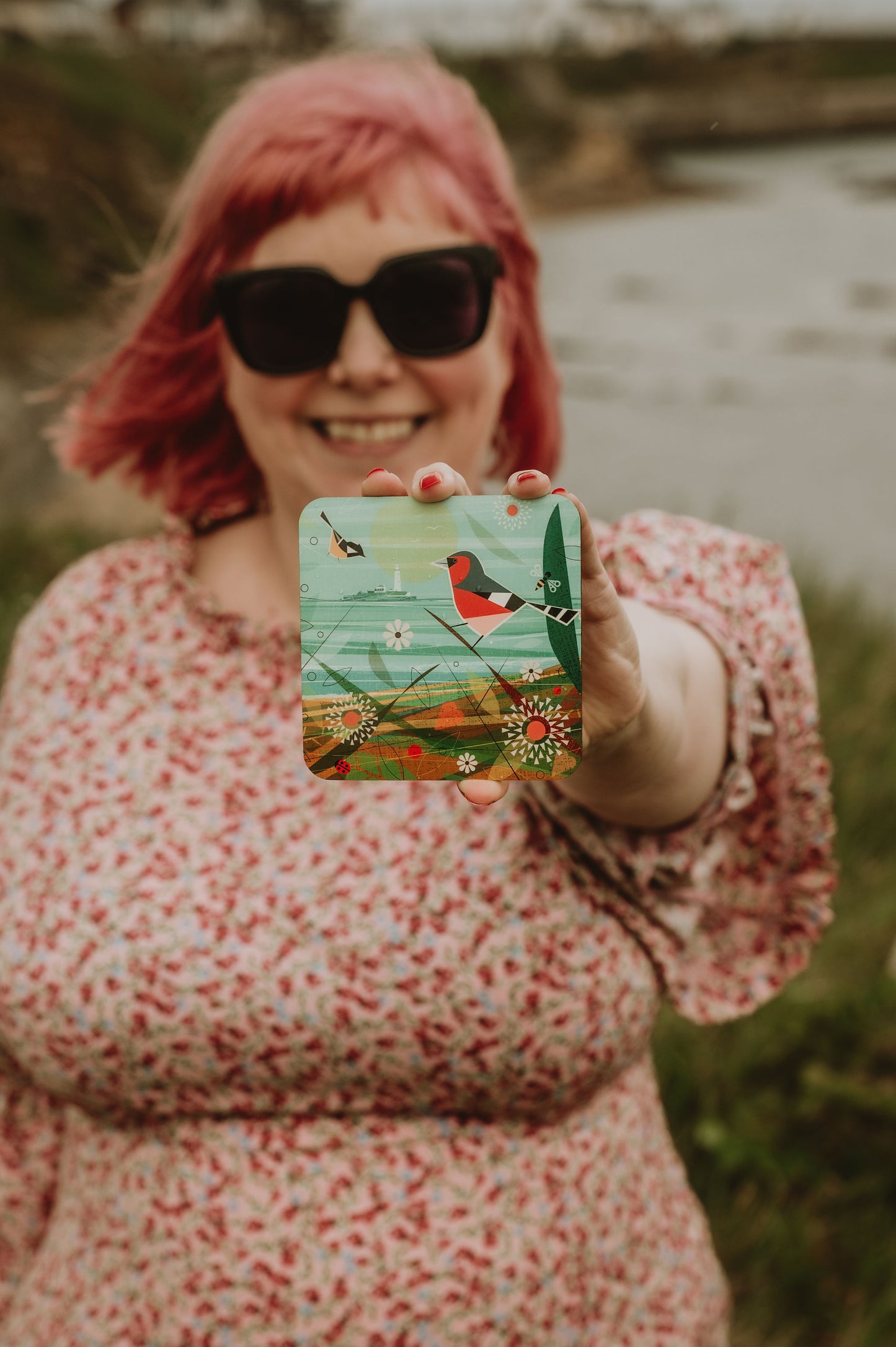 Person holding a coaster with a nature design outdoors