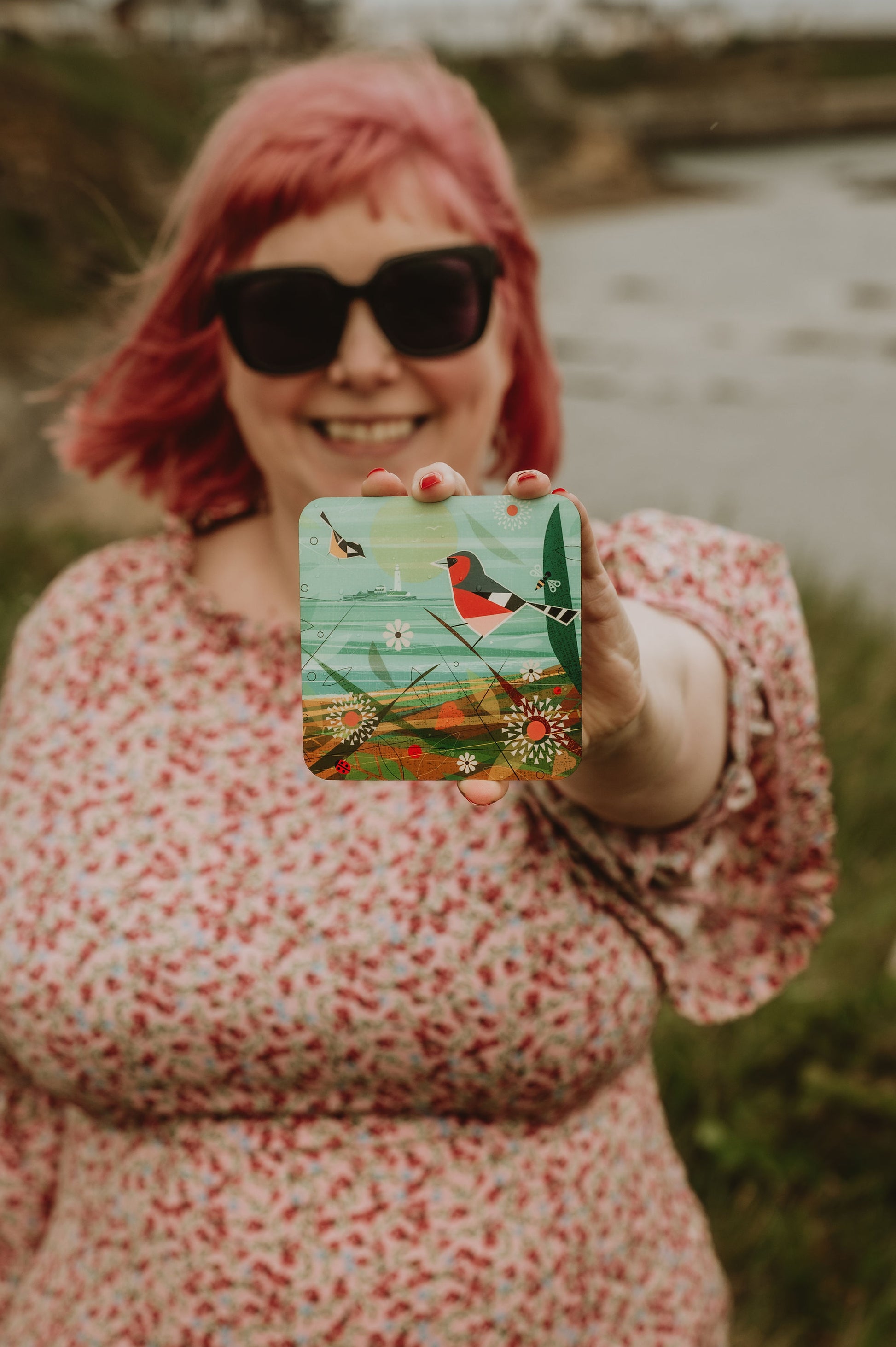 Person holding a coaster with a nature design outdoors